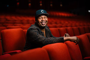 Roy Wood Jr. sitting in a theater with red seats